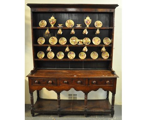 Early 19th Century Welsh oak two stage rack back pot board dresser, the moulded cornice above three Delft shelves with iron h