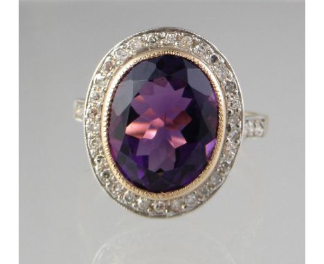 Amethyst and diamond ring . The oval amethyst surrounded by diamonds with diamond set shoulders. Ring size N. Approx weight 5