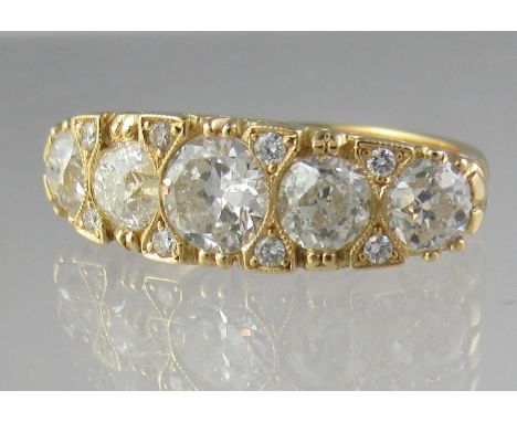 18ct gold five stone ring. The five graduated diamonds separated by diamond points in scroll setting. Estimated total diamond