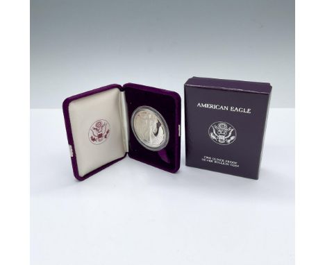 1 ounce silver coin. The obverse side depicts Liberty in full stride, wrapped in folds of the flag and cradling branches of l