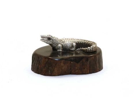 A contemporary silver sculpture of a crocodile by Patrick Mavros, on carved ebony base, with inset button, marked PM, 6cm wid