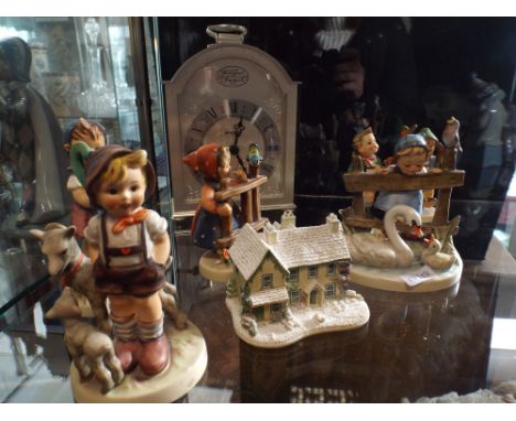 A collection of Hummel figurines of children and a modern quartz carriage style clock 