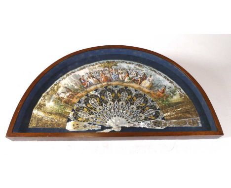 A carved and parcel-gilt mother of pearl fan, printed with a medieval scene, in a fitted wooden frame, 33 x 58cmBroken stem, 
