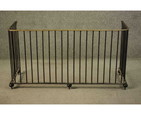 A Victorian black pained wrought iron fireguard, with a brass top rail and ball feet. H.57 W.107 D.40cm. 