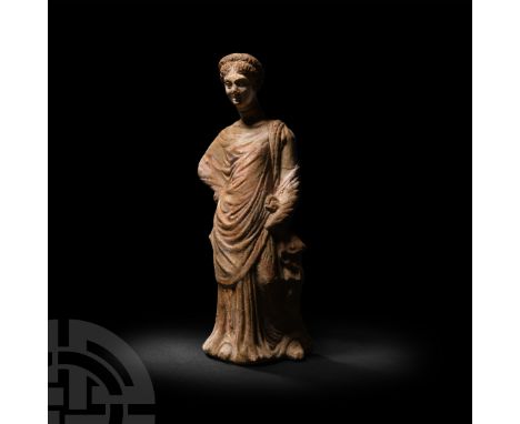 5th-3rd century B.C. A terracotta standing female figure dressed in a floor-length himation, hair drawn back and arranged int