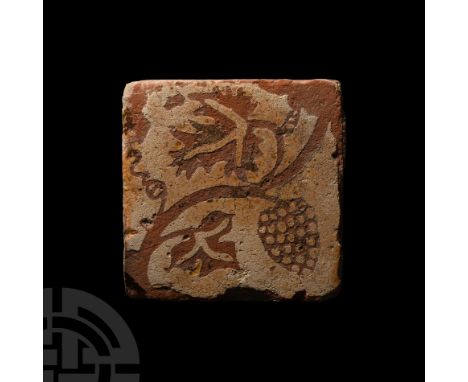 France, 15th century A.D. A square ceramic tile bearing a stamped motif composed of fruiting vines winding diagonally across 