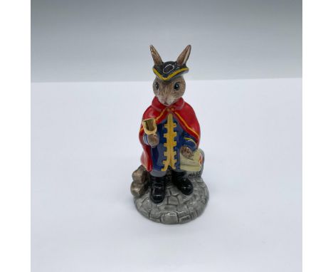 Hand decorated figure of a beige and cream bunny ready to make a public announcement. Shown in a red cape, blue coat with yel