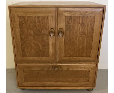 A vintage light elm Ercol 3 door media cupboard with twist lock handles and metal castor feet. Windsor design 2 door cupboard