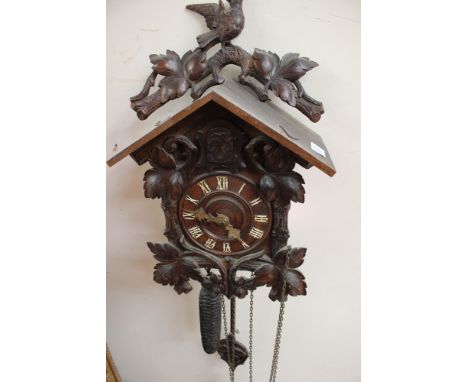 Black Forest carved wood cuckoo clock decorated in leaves and a bird finial with original weights and pendulum (1) 