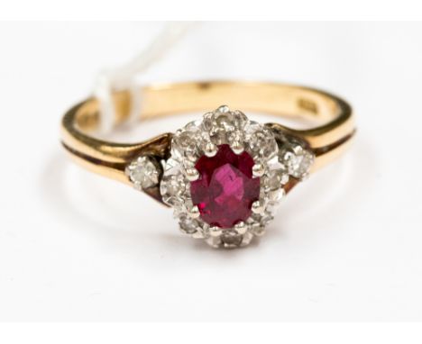  An oval ruby and diamond 18ct yellow gold cluster ring, the centre oval mixed cut ruby measuring approx 5.23 by 4.55 by 2.45