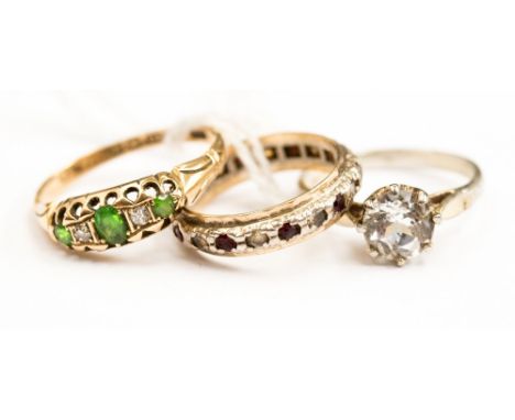 An 18ct gold ring set with diamond chips and three green stones possibly garnet stones, with a white metal eternity ring, set