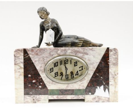 An Art Deco marble cased eight day mantle clock, the case with geometrically inset marble segments, the oval dial with a glas