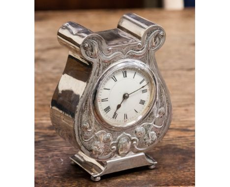 An Edward VII Art Nouveau silver cased mantel clock, embossed floral tendrils, the circular enamel dial with Roman numerals, 