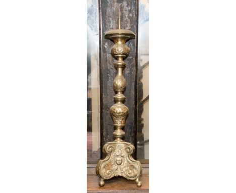 A Spanish style ebonised brass pricket stick, putto mask and floral motifs