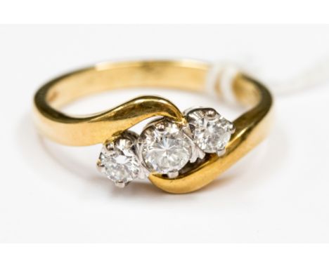 An 18ct diamond three stone ring, with a cross over band, set in 18ct yellow gold with white head, size O, with a total gross