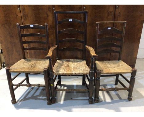 Three antique ladder back chairs with rush seats, two elbow chairs and a white painted wicker armchair