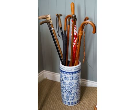 A modern ceramic stick stand containing four umbrellas, six walking sticks and a crop, two of the walking sticks with hallmar