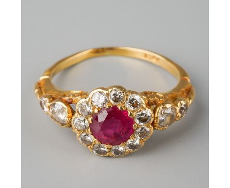 A modern ruby and diamond cluster ring. Set with a central ruby, surrounded by round brilliant cut diamonds, to the round bri