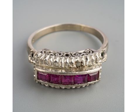 A ruby and diamond dress ring. Set with a line of square shape rubies, surrounded by single cut diamonds, to the plain band, 