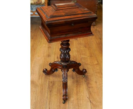 A Victorian rosewood teapoy, the sarcophagus top with hinged cover enclosing a pair of velvet lined circular voids and fitted