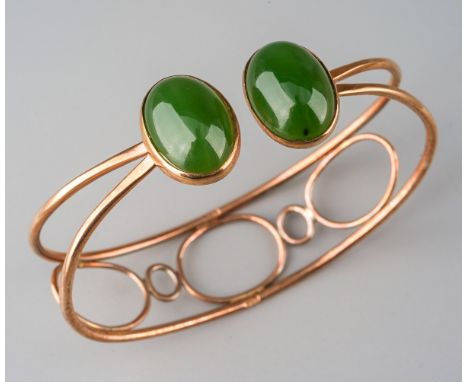 A jade bangle. The torque design bangle set with two oval nephrite jade cabochons, rub over set, to the wirework bangle, stam