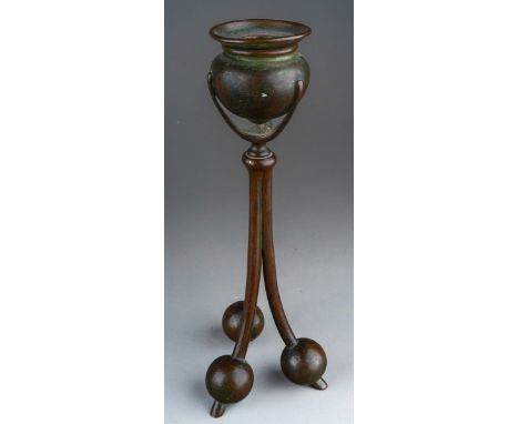 An early 20th Century American Tiffany Studios pattern no 2102 cast bronze candlestick with urn shaped sconce on tripod suppo