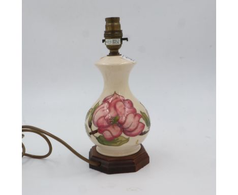 Moorcroft table lamp in the Pink Magnolia pattern on cream ground, raised on a octagonal hardwood base, overall H: 26cm. All 