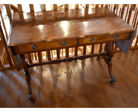 A reproduction mahogany and yew wood crossbanded sofa table, the rectangular top with twin flaps above frieze drawers, raised