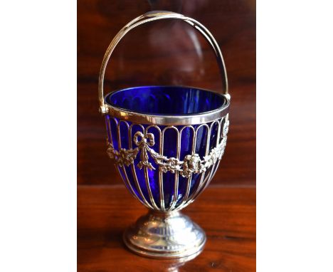 HASELER BROTHERS; an Edwardian hallmarked silver swing handled sugar bowl with blue glass liner, adorned with foliate swag de