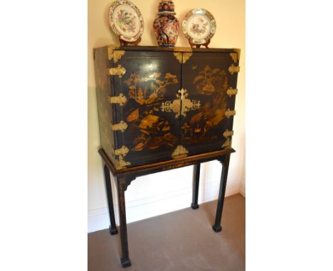 An 18th century Chinoiserie red and black lacquered gold heightened cabinet on stand, the twin hinged doors enclosing an inte