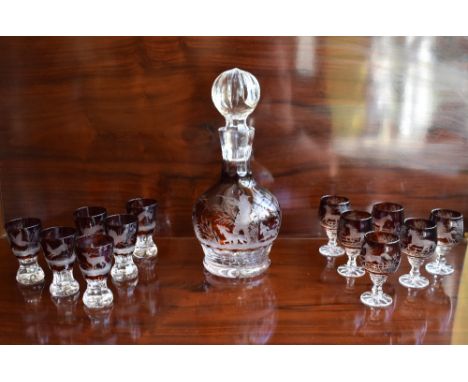 An early 20th century cut glass ruby tinted liqueur set comprising a decanter with substantial stopper above globular body sh