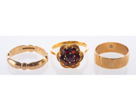 A group of three rings, including a flowerhead ring set with circular-cut garnets, marked 750, size N1/2, 4.6grams; a 9ct yel