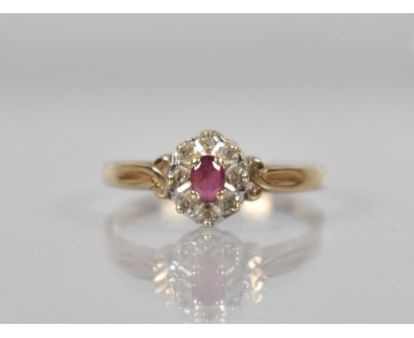 A 9ct Gold, Diamond and Ruby Cluster Ring, Oval Cut Ruby Measuring 3.9mm by 2.8mm Set in Four Claws and Raised on White Metal