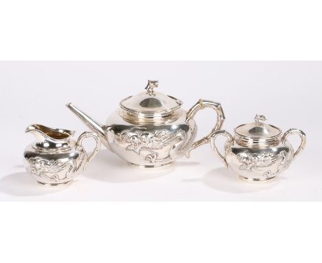 Chinese three piece silver tea service, maker Wang Hing, with dragons curling around the bodies of the teapot, milk jug and l