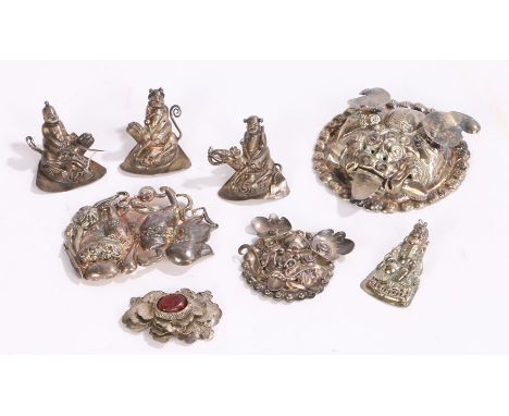 Collection of Chinese white metal amulets, four with figures, two foo dog heads, a dog of foo and a flower head, (8)Overall g