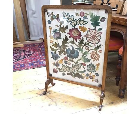 A 1930s firescreen, the embroidered panel with a foliate design, within an oak frame (86cm x 60cm x 22cm)