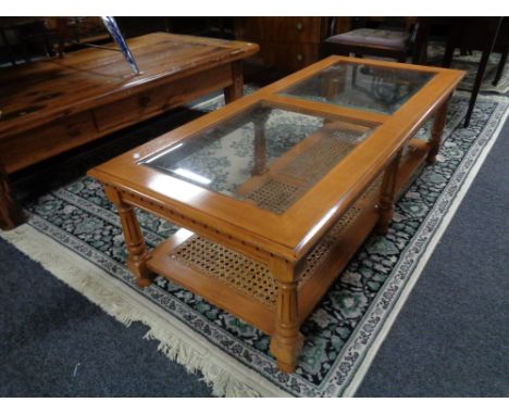 A contemporary rectangular coffee table with two glass inset panels and wicker shelf beneath 