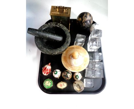 A tray containing glass paperweights, decorative eggs on stands, marble pestle and mortar, a brass battery operated carriage 