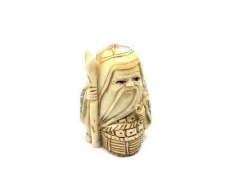 A carved bone Chinese netsuke - Gentleman holding a staff with basket