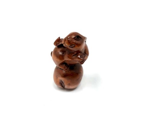 A carved hardwood Chinese netsuke - Rabbit standing on a fruit