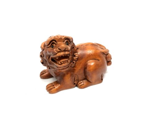 A carved hardwood Chinese netsuke - Lion seated