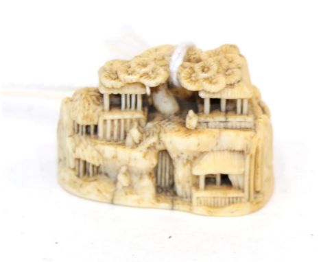 A Japanese Ivory Netsuke, Meiji period, carved as figures and buildings in a rocky landscape, signed, 3.5cm wide