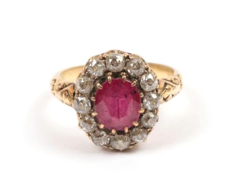 A Red Stone and Diamond Cluster Ring, the oval cut red stone within a border of old cut diamonds, to engraved shoulders on a 