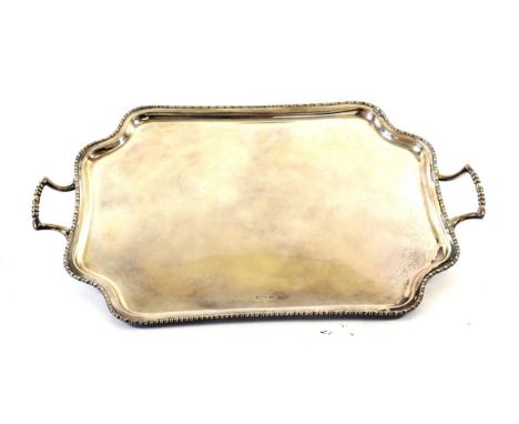 A George V Silver Tray, by Atkin Bros., Sheffield, 1910, shaped oblong and with beaded rim, on four button feet, 60cm wide ov