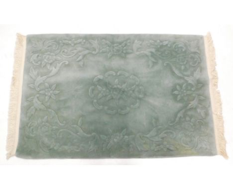 A Chinese green jade coloured rug, with raised decoration of flowers, leaves, etc., 177cm x 124cm.