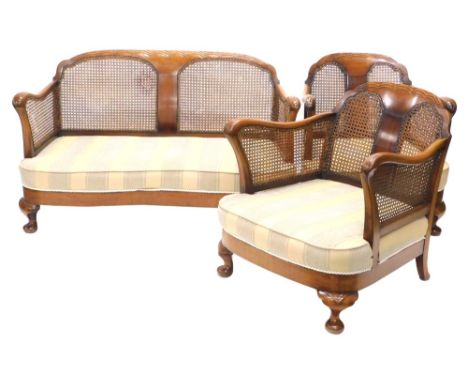 An early 20thC walnut bergere suite, comprising two seater sofa with cane filled back and arms, striped cushions on short cab