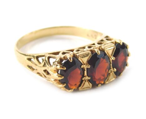 A ladies 9ct gold garnet dress ring, with three claw set faceted cut stones on a pierced shank decorated with hearts, size N-