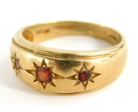 A dress ring, marked 9k, set with three small garnets, size R/S, 5.3g all in.