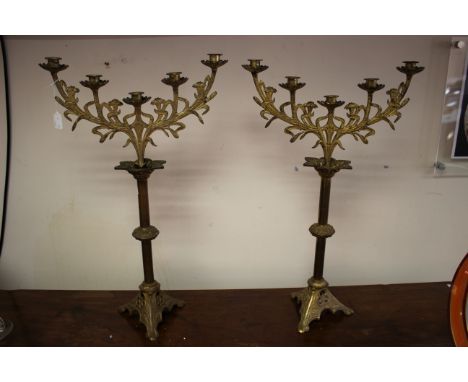 A pair of Arts and Crafts gilt metal candelabra, the knopped cylindrical columns on pyramidal bases each supporting a five li