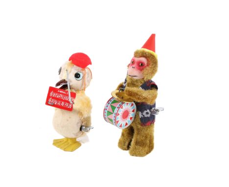 Two vintage clockwork mechanical toys. Comprising a 1950's 'Mr Duck' figure holding a music score and baton and a monkey beat